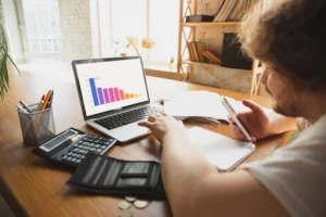 A man sits in front of a laptop with a graph on it