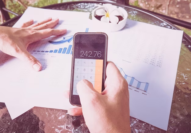 Hands of a man using a calculator on a phone with graphs